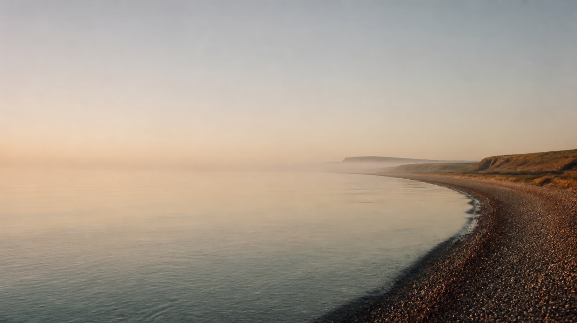 A calm shoreline at first light, stretching into the distance